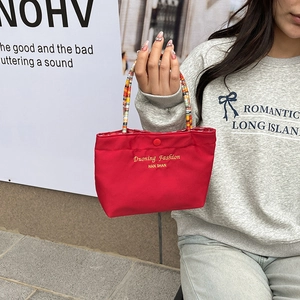 Chic red fabric handbag with colorful woven handles and snap closure for casual use