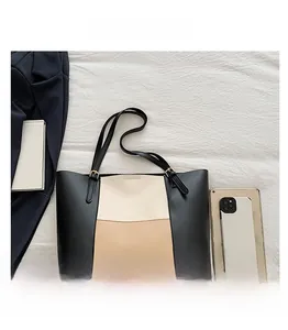 Detail view of large color-block tote bag with gold hardware on white textured fabric