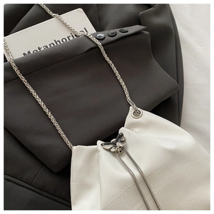 Détail du sac seau blanc à texture crocodile avec fermoir papillon argenté et chaîne