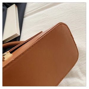 Vue détaillée de la couture du sac marron et de la boucle métallique dorée