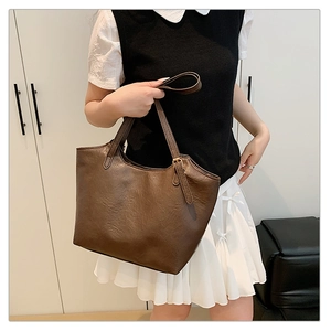 Detail of a large brown pebble leather tote bag with a golden metal buckle on the shoulder strap