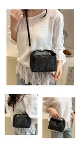 Detail view of black snakeskin texture bucket bag with metallic buckle closure and strap