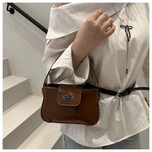 Détail du sac bandoulière marron en similicuir avec plaque métallique et rabat aimanté