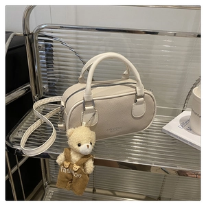 Detail of cream bowling bag with pebble grain leather texture and a cute bear charm