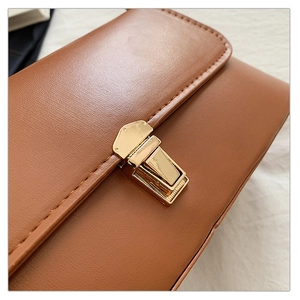 Gros plan sur la boucle dorée rectangulaire du sac à main en cuir marron