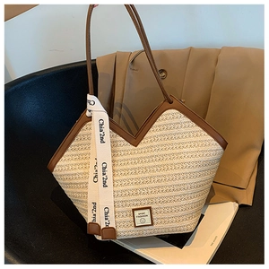 Detail of beige woven tote bag with V-shaped leather trim and silk scarf on black chair