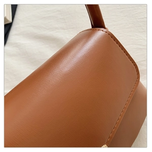 Vue macro de la texture du cuir marron caramel et des coutures d'un sac à bandoulière