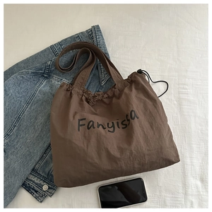 Detail of brown canvas tote bag with drawstring closure and black Fanyissa lettering