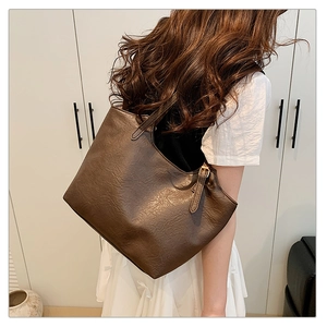 Dettaglio della borsa tote marrone caffè con trama vintage e fibbia in metallo sulla tracolla