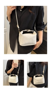 Close-up of white snakeskin texture handbag with gold hardware and removable shoulder strap