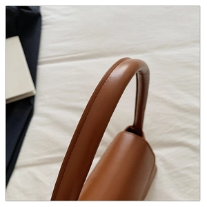 Gros plan de la poignée du sac en cuir marron avec coutures détaillées et texture chic