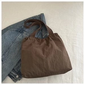 Detail of dark brown tote bag featuring drawstring closure and textured nylon fabric