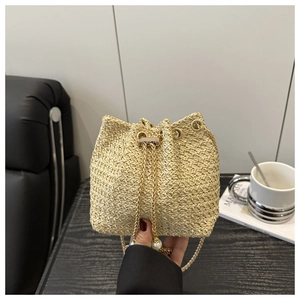 Detail of straw bucket bag featuring pearl drawstrings and golden chain strap