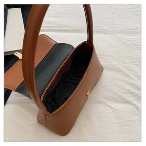 Détail d'un sac bandoulière en cuir marron avec fermoir tournant doré sur tissu blanc