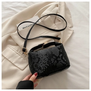 Detail of fashion black snake-patterned leather shoulder bag with textured finish