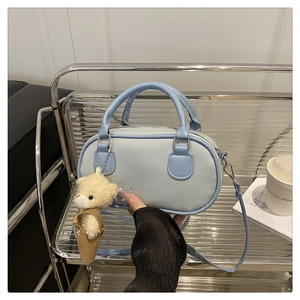 Detail of light blue lychee pattern Boston bag with teddy bear pendant on display shelf