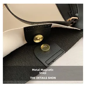 Detail of the golden magnetic hardware clasp on a black and white contrast leather tote bag
