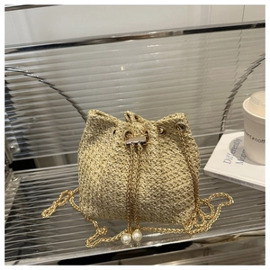 Detail of woven straw bucket bag with gold chain strap and decorative white pearls