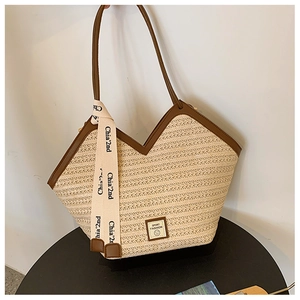 Detail of woven straw tote bag with brown leather trim and decorative silk scarf