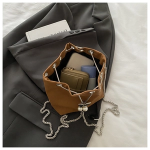 Détails du sac seau caramel à cordon avec chaîne argentée et pendentif perle élégant