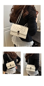 Detail of white quilted crossbody bag with chevron pattern and metal chain strap