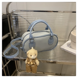 Detailed view of light blue lychee pattern bowling bag with cute teddy bear charm