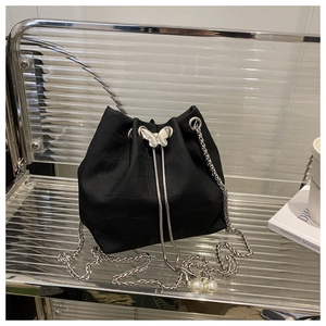 Détail du sac seau noir motif crocodile avec fermoir papillon argenté et perles élégantes