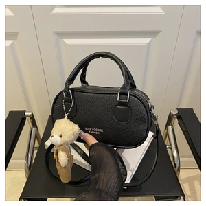 Detail of black litchi grain bowling bag with silver hardware and plush bear charm