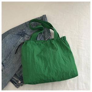 Detail of green water-resistant nylon tote bag with drawstring and wrinkled texture