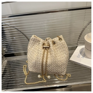 Detail of beige woven bucket bag with elegant pearl drawstring and gold chain strap