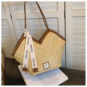 Detail of woven straw tote bag with brown leather trim and chic decorative ribbon
