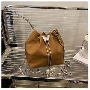 Détail du sac seau marron à motif crocodile avec papillon argenté et breloque en perles