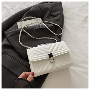 Detailed view of white quilted shoulder bag featuring V-shaped stitching and silver chain