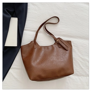 Dettaglio della borsa tote in pelle marrone con texture sottile e tracolla sottile