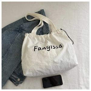 Close-up of white Fanyissa drawstring tote bag made of textured nylon on a bed