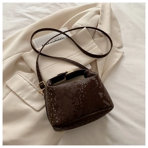 Detail of dark brown faux-crocodile texture with gold hardware on minimalist bucket bag