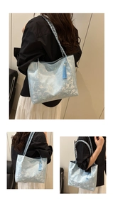 Detail of light blue floral jacquard tote bag with braided handles and stylish fringe tassel