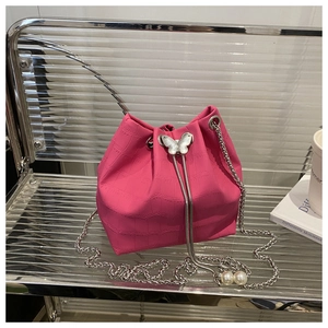 Détail du sac seau fuchsia avec texture crocodile, papillon argenté et cordon en perles