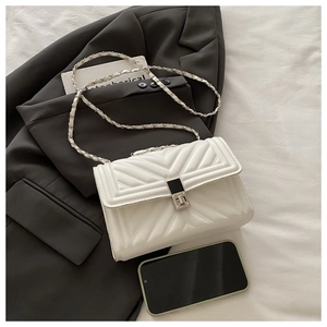 Detail of white V-quilted faux leather crossbody bag with silver chain strap and metal clasp