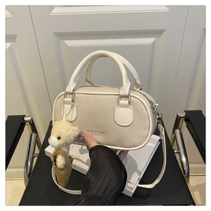 Detail of off-white bowling bag with pebble texture, brand logo, and a cute bear charm