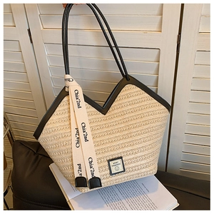 Detail of woven straw tote bag featuring leather trim and sport fashion smile patch