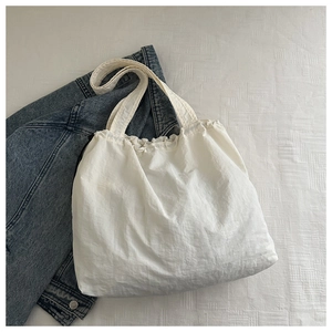 Detail of white pleated canvas tote bag with ruffled edges and large capacity design