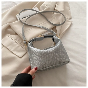 Detail of silver snake-pattern textured shoulder bag with gold hardware on white blazer