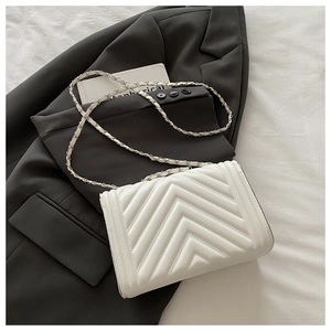 Detail of white chevron quilted handbag with gold chain strap and leather texture