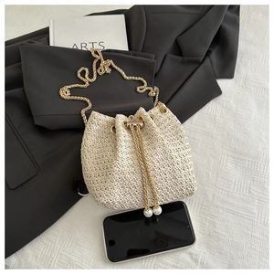 Detail of woven bucket bag with gold chain strap and pearl drawstring accents