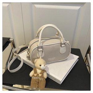 Mini cream bowling bag on a book with cute teddy bear charm and soft lighting setup