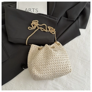 Detail of cream woven bucket bag showing dense texture and gold chain strap on blazer