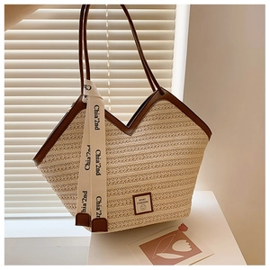 Detail of beige woven tote bag with brown handles, ribbon and smile sport patch