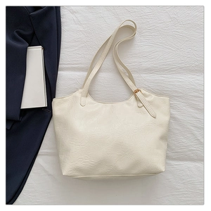 Dettaglio della borsa tote color crema in pelle pieghettata morbida con fibbia dorata