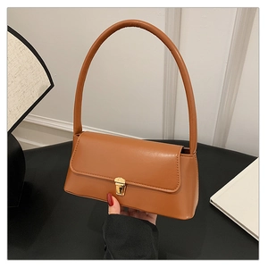 Détail du sac sous le bras en cuir marron caramel avec boucle dorée et bandoulière